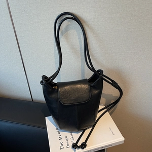Minimalist black bucket bag with slim shoulder straps on a design book for daily commute