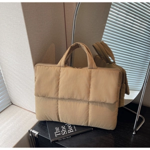Detailed view of khaki quilted handbag with smooth matte texture and top zip closure