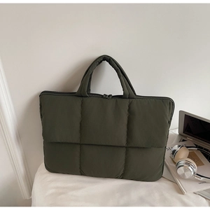 Detailed close-up of dark green quilted laptop bag with soft padding and zip closure