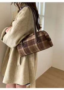 Side view of a vintage plaid wool shoulder bag with leather straps on a female model