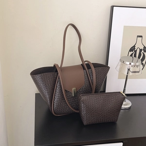 Deep brown woven leather tote bag set with matching clutch in a modern indoor setting