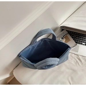 Top view of blue quilted laptop bag with spacious interior and laptop on bed