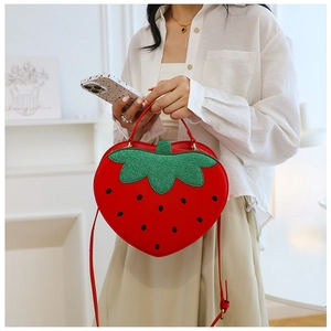 Close-up of heart-shaped strawberry bag with green leaf detail and gold hardware