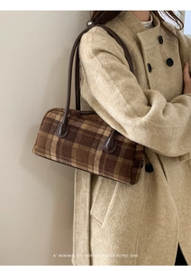 Detail of retro brown plaid woolen handbag with leather handle styled on beige coat