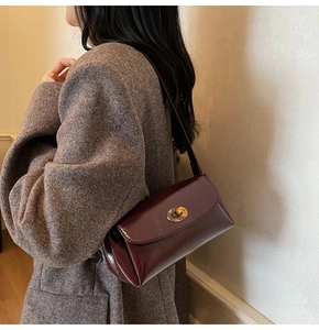 Detail of burgundy crossbody bag with vintage gold clasp on model during fall
