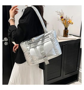 Gros plan d'un sac cabas argenté matelassé avec boucle décorative et fermeture éclair