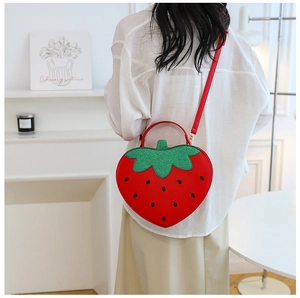 Detail of strawberry crossbody bag showing back view of red PU leather model in white room