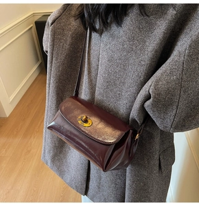 Detail of dark burgundy vintage leather crossbody bag with metallic turn-lock closure