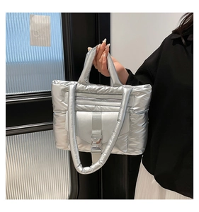 Détail du sac matelassé argenté avec doubles poignées et poche à boucle métallique