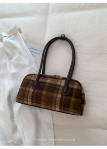 Detailed view of a brown plaid textured shell bag with premium leather handles