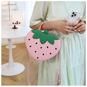 Detail of cute strawberry shaped pink crossbody bag with green sequin leaves for girls