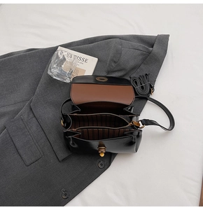 Detailed interior of vintage black leather flap bag with dual compartments and striped lining