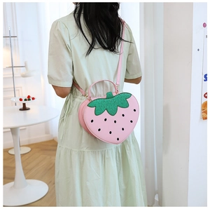 Detail of pink strawberry-shaped handbag with green sequins and adjustable strap