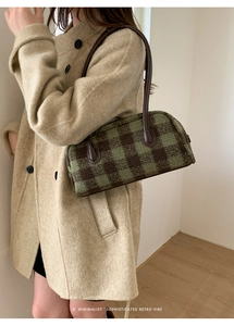 Detail of retro green and brown plaid baguette bag with leather strap on beige coat