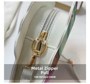 Detailed close-up of the premium golden metal zipper head on a white leather heart bag