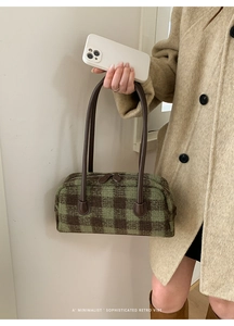 Detail of retro green plaid shell bag with brown leather handles and zipper closure