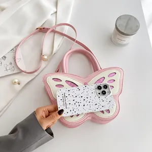 Bolso rosa con forma de mariposa comparación de tamaño con un móvil y accesorios