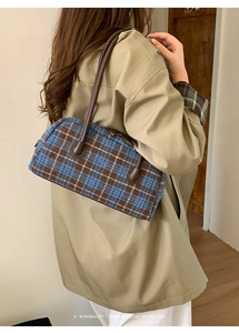 Shoulder view of a textured plaid handbag with leather handles for autumn fashion