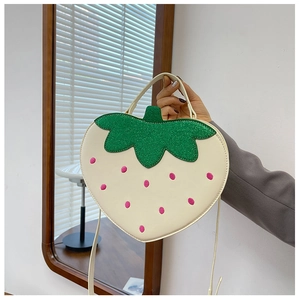 Detail of strawberry shaped crossbody bag with green glitter leaves and pink embroidery