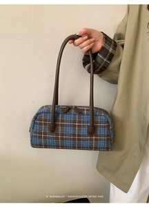 Macro view of textured plaid fabric and premium leather handle on retro shell bag
