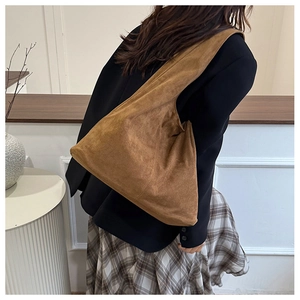 Detail of the large brown suede shoulder bag showing texture and drape on a model