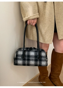 Detail of retro black and white plaid wool handbag with sleek black leather handles