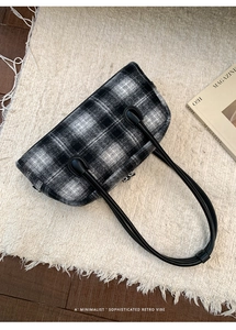 Detail of wool texture and leather strap on retro black and white plaid shell bag