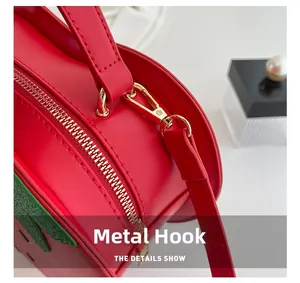 Detail shot of strawberry bag featuring gold metal hooks and red textured leather