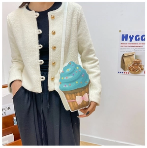 Cute cupcake crossbody bag with blue frosting and pink bow shown in a lifestyle setting