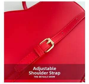 Detail of red leather shoulder strap with golden metal buckle and stitching