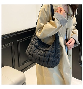 Side view of a black quilted cloud hobo bag worn with a beige trench coat for a chic look