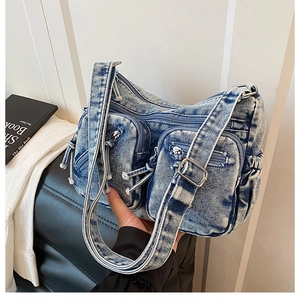 Gros plan du sac bandoulière en jean bleu délavé avec plusieurs poches zippées utilitaires