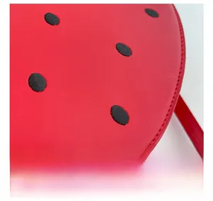 Macro shot of precise stitching and black embroidery on red leather strawberry bag