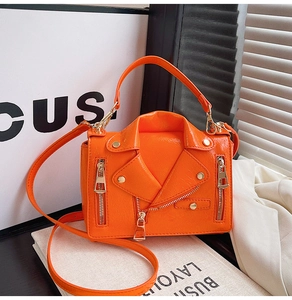 Detail of orange leather motorcycle style crossbody bag with metal zippers and rivets