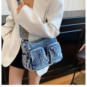 Détail du sac bandoulière en jean bleu avec poches avant sur un mannequin en blazer blanc