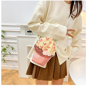 Pink cupcake crossbody bag styled with a beige knit top and corduroy skirt in a home setting