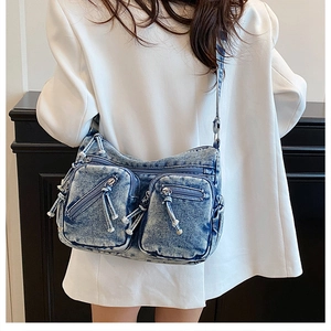 Détail du sac bandoulière en denim bleu avec plusieurs poches et bandoulière réglable