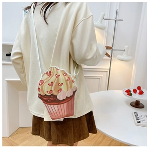 Detail shot of a cupcake-shaped crossbody bag featuring heart prints and a cream-colored top