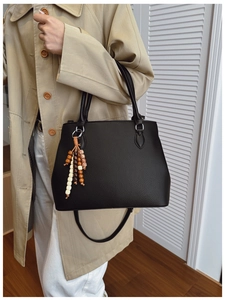 Detail of black pebbled leather tote bag with colorful wooden bead tassel accessory
