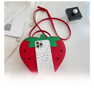 Detailed view of red strawberry crossbody bag with green leaf accents and size reference