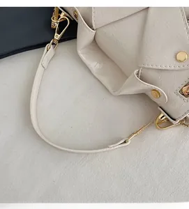 Detail shot of cream textured leather bag with gold rivets and metallic buckle hardware