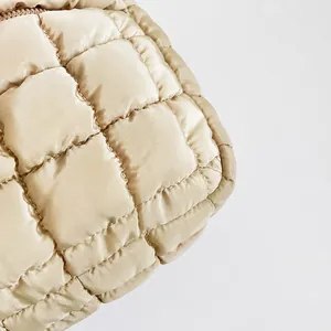 Detailed macro view of beige quilted nylon cloud bag fabric with precise stitching