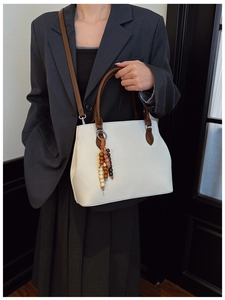 Detail of white lychee leather tote bag with vintage wood bead charm and brown straps