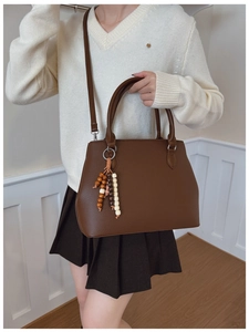 Detail of brown litchi pattern leather tote bag with vintage beaded charm and strap