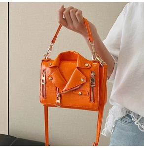 Detail of bright orange biker jacket style bag with golden zippers and studs
