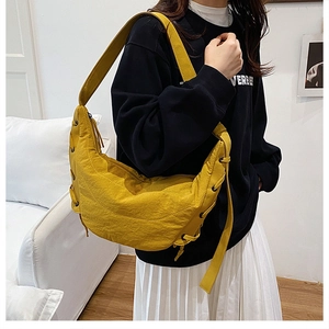 Close-up of yellow large hobo bag with side lace-up details and wide shoulder strap