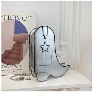 Détail du sac bandoulière argenté en forme de botte avec écusson étoile et chaîne