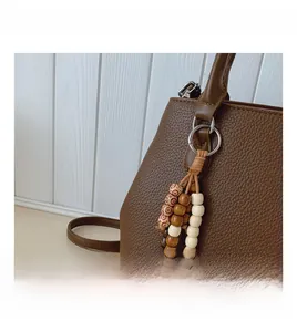 Close-up of brown lychee grain leather tote with colorful vintage wooden bead charm