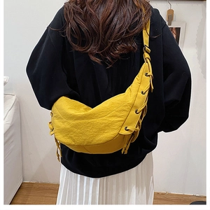 Detail of yellow crescent bag with textured fabric and drawstring knots on a model