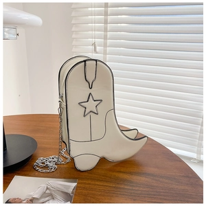 Détail d'un sac à bandoulière en forme de botte de cowboy blanche avec surpiqûres noires